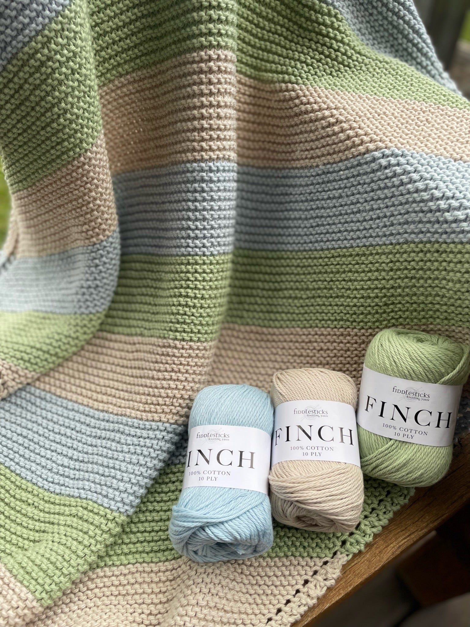 Fiddlesticks Finch 10 ply Cotton Yarn. Striped knit blanket in green, blue and beige yarn.